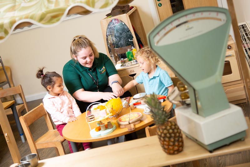 staff member and children play at table indoors