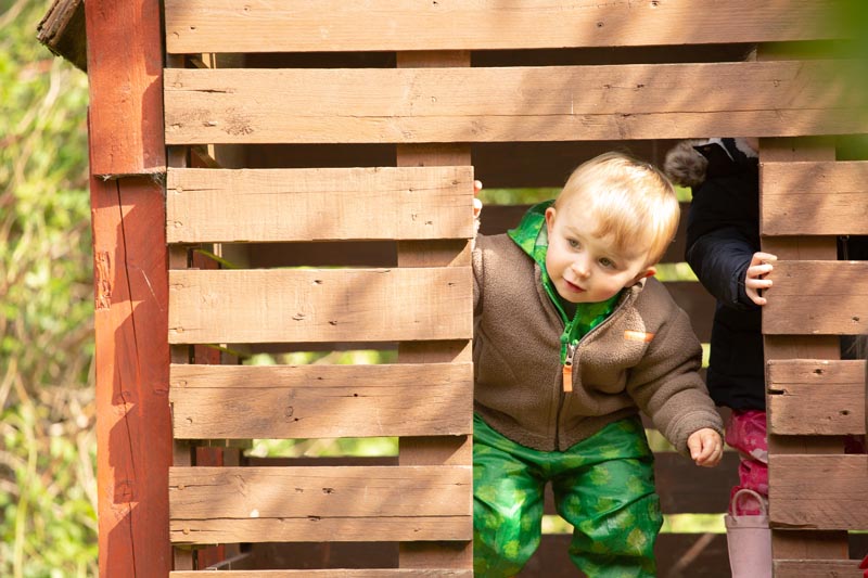 little boy in wooden play hut