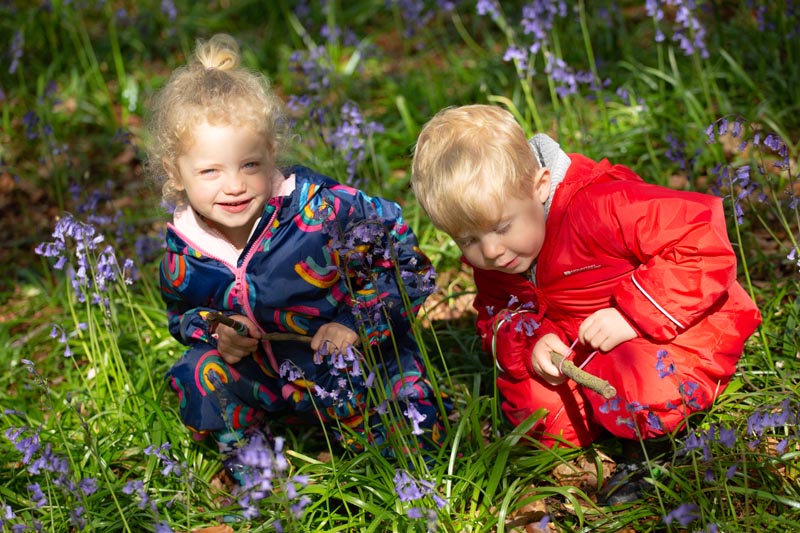 girl and boy playing near bluebells